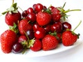 Juicy strawberries and cherries on white plate