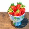 Juicy strawberries fill a dainty cup, ripe and enticing