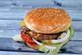 A juicy thick double beef patty with cheese covered with sauce, crispy lettuce, fresh tomatoes, onions and pickles in a large Royalty Free Stock Photo