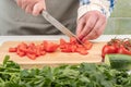 A juicy tomato is cut into small pieces on a wooden cutting board. Royalty Free Stock Photo