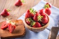 Juicy washed strawberries in wooden bowl on kitchen table