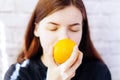 Juicy, yellow orange in the girl`s hand. A young woman enjoys the smell of an orange. A young girl with a ripe clementine in her h