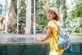 Happy visitor woman in botanical tropical garden with pond