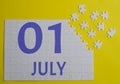 1 july calendar date on a white puzzle with separate details. Puzzle on a yellow background with a blue inscription