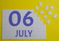 6 july calendar date on a white puzzle with separate details. Puzzle on a yellow background with a blue inscription