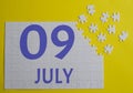 9 july calendar date on a white puzzle with separate details. Puzzle on a yellow background with a blue inscription