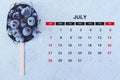 July calendar. Stack of frozen sweet cherries with July month calendar. Summer Royalty Free Stock Photo