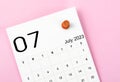 A July 2023 calendar and wooden push pin on pink colour background