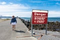 CRESCENT CITY CA: Despite the warning on the sign not to walk on the jetty, a female tourist ignores the sign,