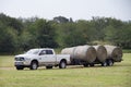 Ram pickup with load of large round bales of hay on a trailer