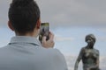 July, 8 2018 - A man photographs with smartphone the Little mermaid statue in Copenhagen Denmark under a cloudy sky