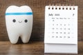 The July 2023 Monthly desk calendar for 2023 year with Model tooth on wooden table
