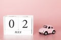 July 02nd. Day 2 of month. Calendar cube on modern pink background with car