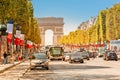 Buses and cars drive along Avenue Champs Elysees with the Arc de Triomphe in the background