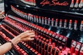 girl chooses pink shiny lipstick in the women`s cosmetics store