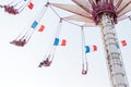 People relax in an amusement Park on a high-rise carousel with French flags waving in the wind