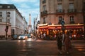 Warm and cozy evening in Paris with people crossing the street, small cafe and the Eiffel tower in