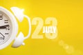 July 23rd. Day 23 of month, Calendar date. White alarm clock on yellow background with calendar day. Summer month, day of the year