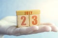 july 23rd. Day 23 of month,Handmade wood cube with date month and day on female palm summer month, day of the year concept