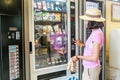 Woman buying chips and other snacks from automatic vending machine