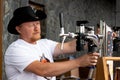 July 07, 2018, Russia, Konakovo. Man with beard and whiskers pouring beer from a tap at local festival or outdoor cafe, wearing bl