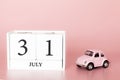 July 31st. Day 31 of month. Calendar cube on modern pink background with car