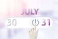 July 31st . Day 31 of month, Calendar date.Hand finger switches pointing calendar date on sunlight office background. Summer month