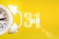 July 31st . Day 31 of month, Calendar date. White alarm clock on yellow background with calendar day. Summer month, day of the