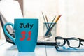 July 31st. Day 31 of month, color calendar on morning coffee cup at manager workplace background. Summer time. Empty