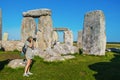 Woman photographer in shorts takes a picture inside the standing stones at Stonehenge while father