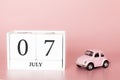 July 07th. Day 7 of month. Calendar cube on modern pink background with car