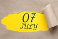 july 07. 07th day of the month, calendar date.Hole in paper with edges torn off. Yellow background is visible through