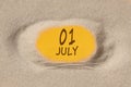 July 1. 1th day of the month, calendar date. Hole in sand. Yellow background is visible through hole