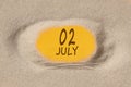 July 2. 2th day of the month, calendar date. Hole in sand. Yellow background is visible through hole