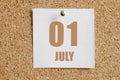 july 01. 01th day of the month, calendar date.White calendar sheet attached to brown cork board.Summer month, day of the
