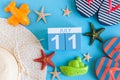 July 11th. Image of july 11 calendar with summer beach accessories and traveler outfit on background. Summer day