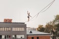 Male athlete demonstrates his skills by balancing on a narrow slackline stretched between two buildings Royalty Free Stock Photo