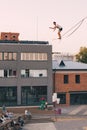 Male athlete demonstrates his skills by balancing on a narrow slackline stretched between two buildings Royalty Free Stock Photo