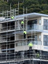 July 15, 2021. Workers closeup disassembling scaffolding on now completed top floors of home unit block at 56-58 Beane St