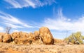 A jumble of granite boulders, blue sky with strange clouds and dry grass landscape Royalty Free Stock Photo