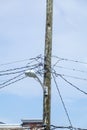 Jumble of wires connecting to the top of a wooden telephone utility pole with a street light attached to it Royalty Free Stock Photo