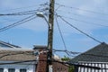 Jumble of wires connecting to the top of a wooden telephone utility pole with a street light attached to it Royalty Free Stock Photo