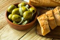 Jumbo gordal olives with herbs and onions with rustic baguette on wood background