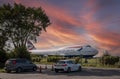 A 747 jumbo jet minus the engines waits to be broken up under a sunset sky.