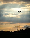 Jumbo jet silhouette with runway lights silhouette flying off taking tourists abroad from airport on holiday into golden sunset