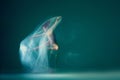 Contemp dance. Creative portrait of flexible ballet dancer in motion with white cloth over green blue background. Art Royalty Free Stock Photo