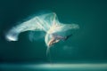 Contemp dance. Creative portrait of flexible ballet dancer in motion with white cloth over green blue background. Art Royalty Free Stock Photo