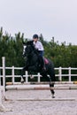 Jump over barrier. Young sportive girl, teen training at riding arena in summer day, outdoors. Dressage of horses Royalty Free Stock Photo