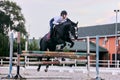 Jump over barrier. Young sportive girl, teen training at riding arena in summer day, outdoors. Dressage of horses Royalty Free Stock Photo