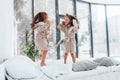 Jumping on bed. Two cute little girls indoors at home together. Children having fun Royalty Free Stock Photo